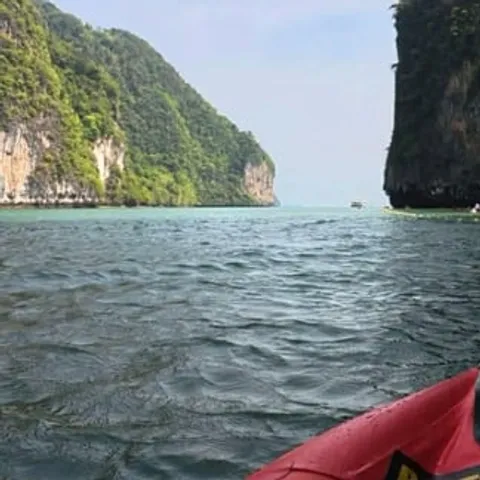 The bow of a sea canoe heading towards limestone cliffs