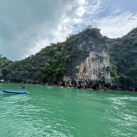 Canoes on turquoise water below limestone cliffs