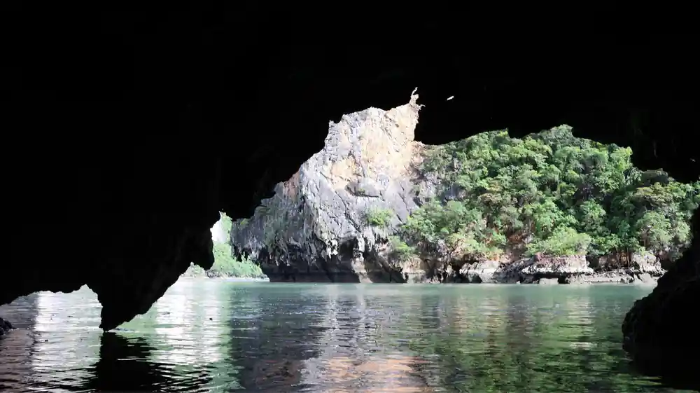Cave opening frames limestone island with vegetation