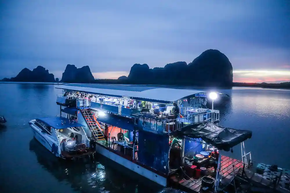 Floating restaurant barge at dusk with limestone backdrop