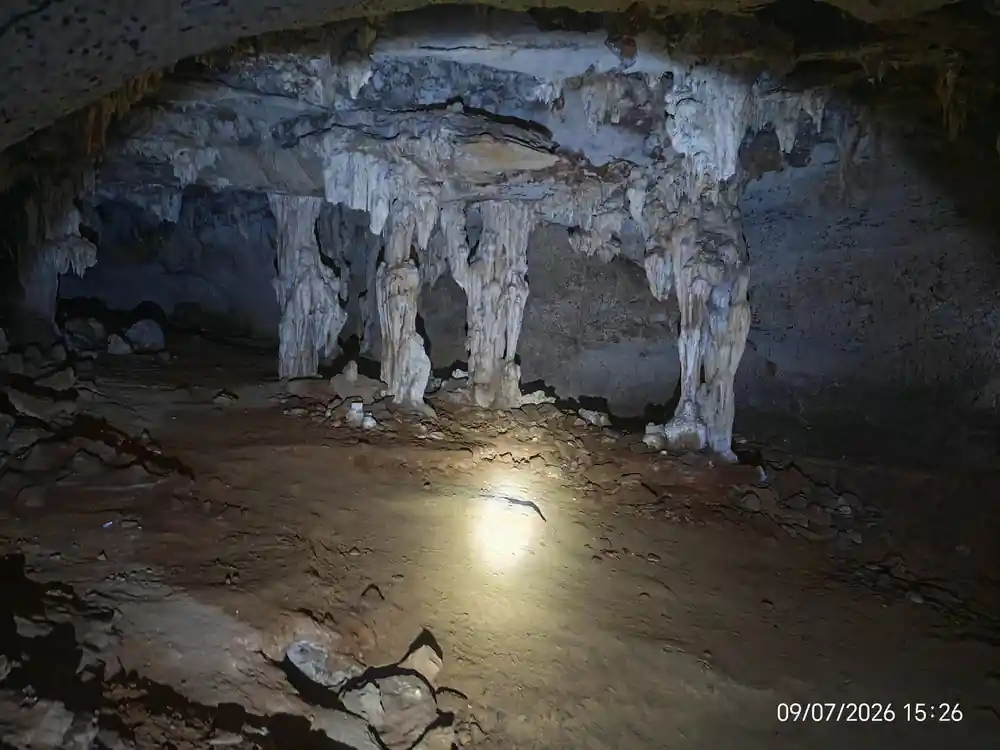 Inside cave looking out at kayakers in emerald water