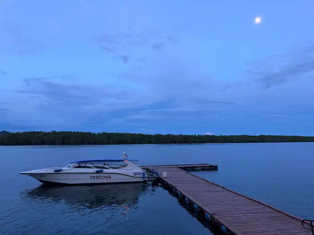 Motorboat moored at wooden dock at twilight