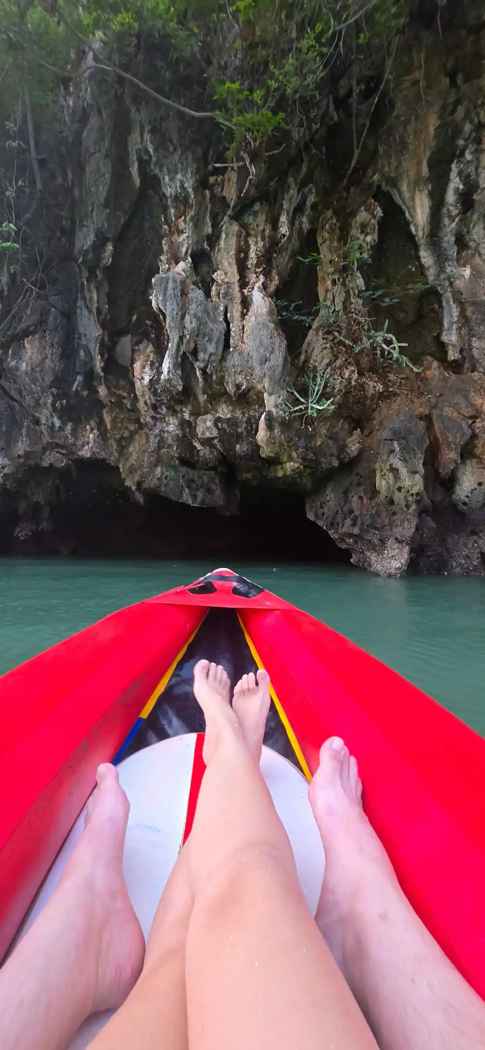 Red kayak approaching cave mouth in turquoise water