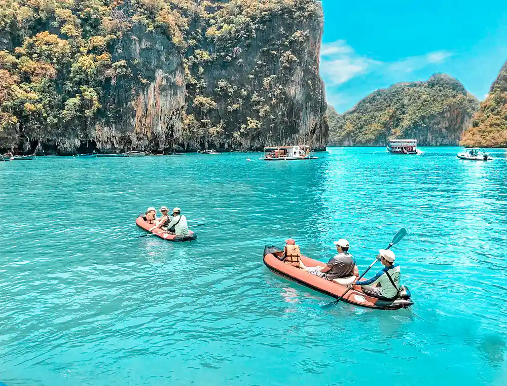 Red and orange kayaks near tall limestone cliffs