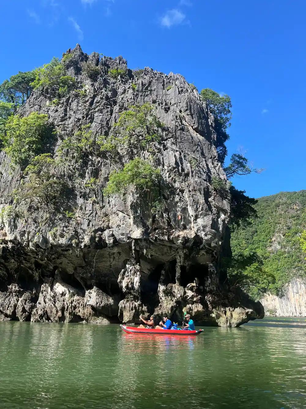 Rocky island with tourists in kayak below
