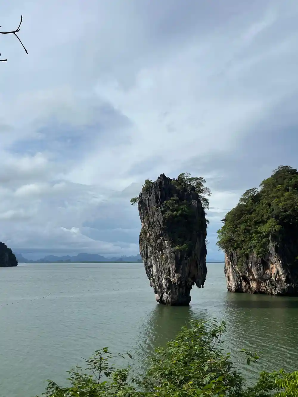 Single tall limestone tower emerging from shallow turquoise water