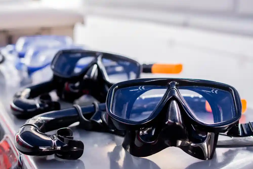 Snorkeling masks and fins on white surface