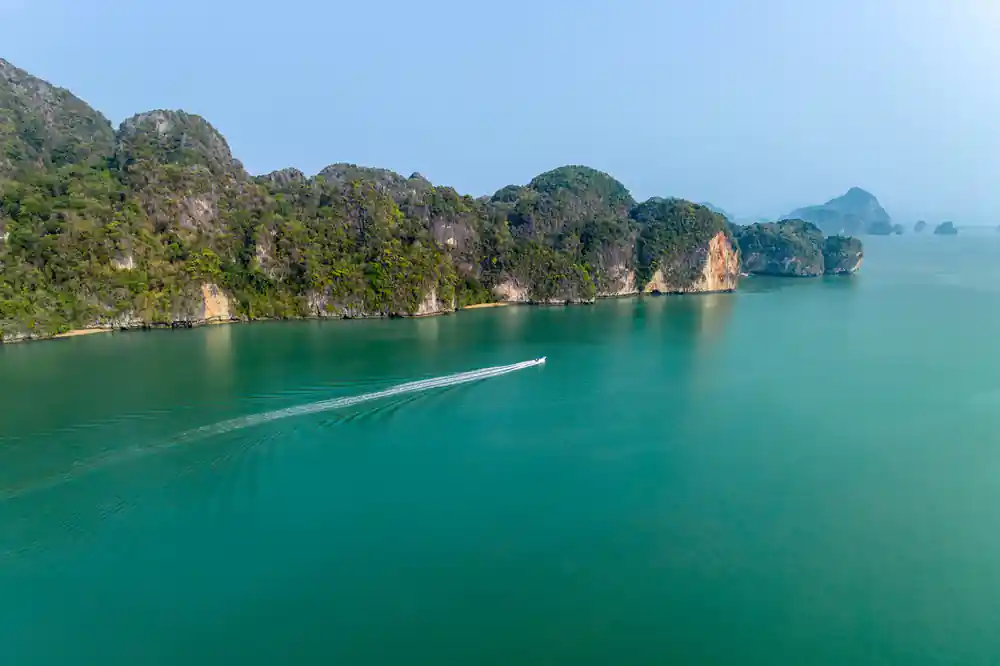 Speedboat traveling past limestone islands in turquoise bay
