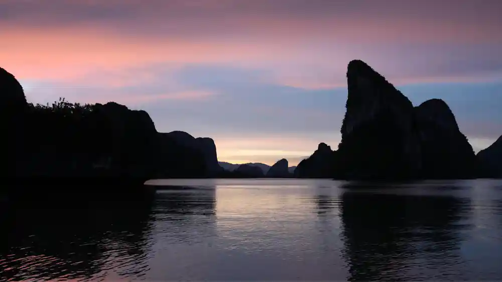 Sunset silhouettes of limestone karst rocks in water