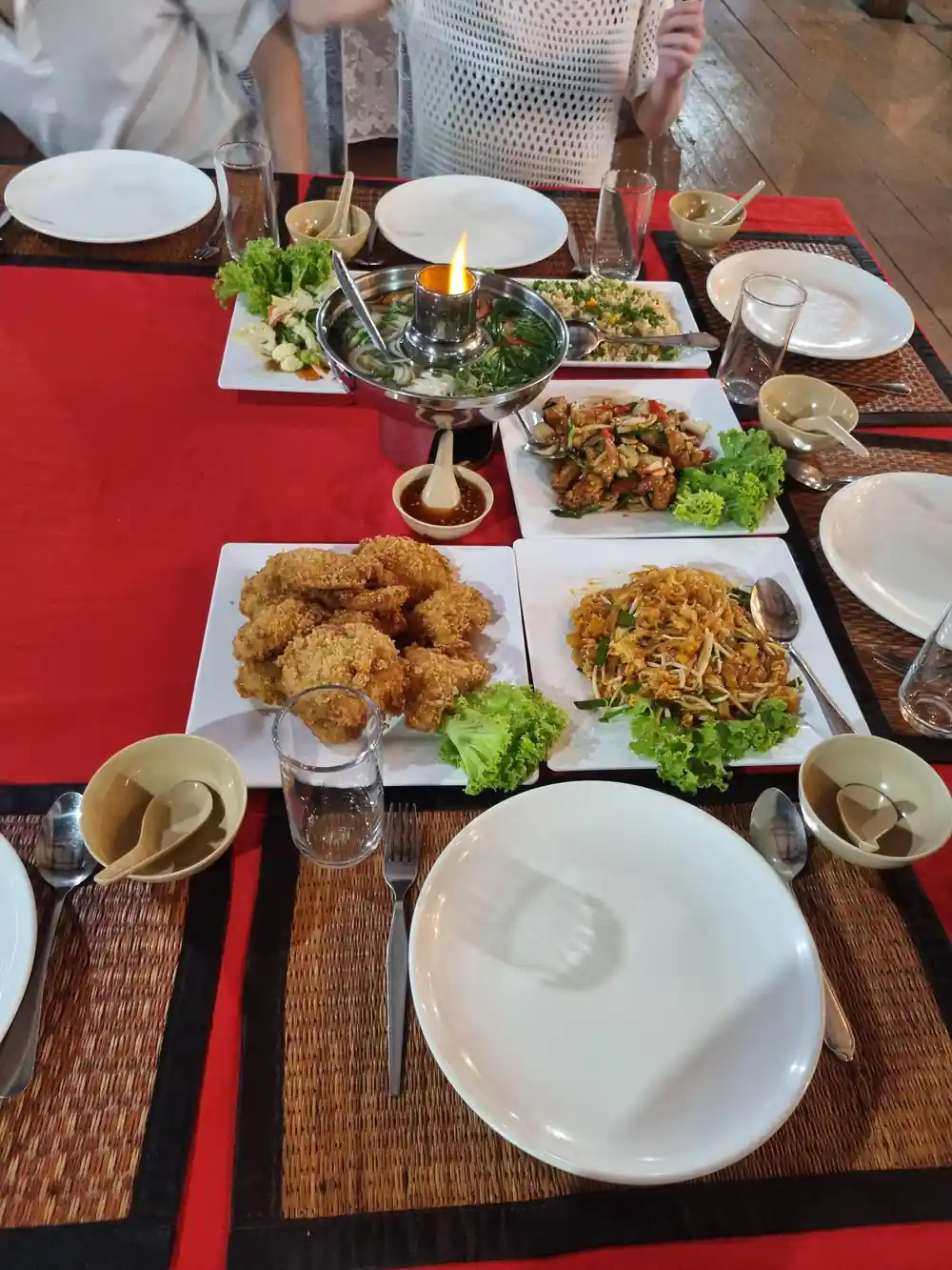 Table with multiple dishes of Thai food and drinks