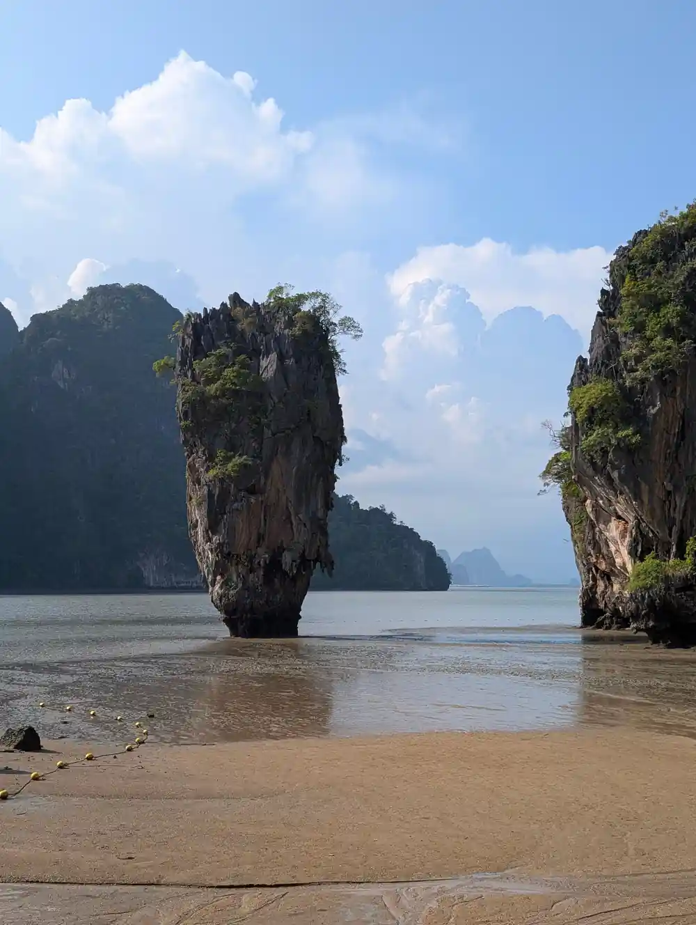 Tall limestone rock island between water and beach