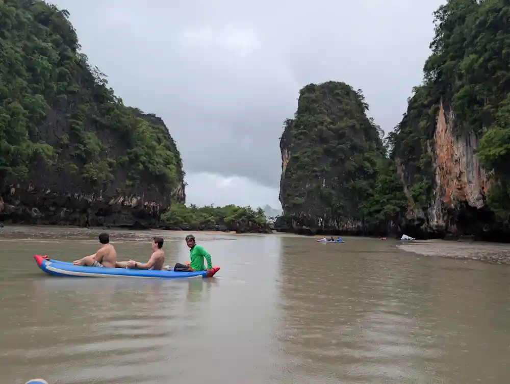 Three men in small boat between limestone cliffs