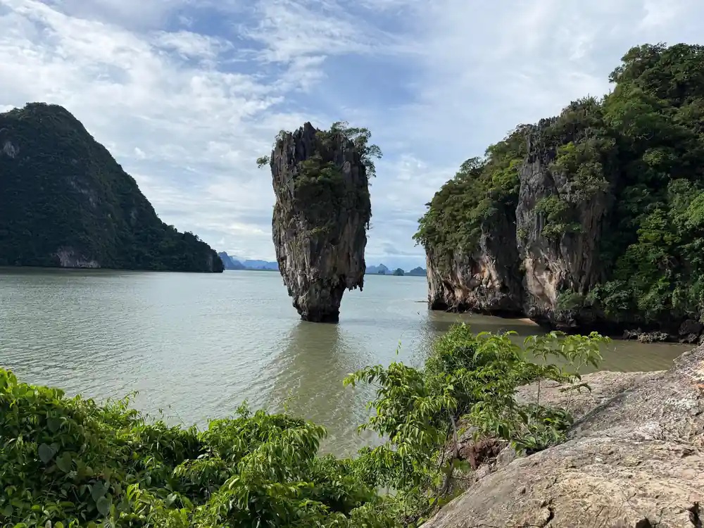 Twin limestone islands in bay viewed from sandy beach with vegetation