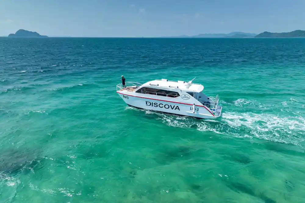 White speedboat named Discova in shallow turquoise water