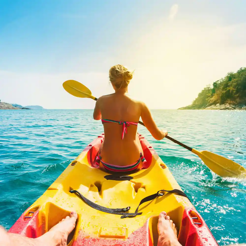 Woman paddling yellow kayak in turquoise tropical water