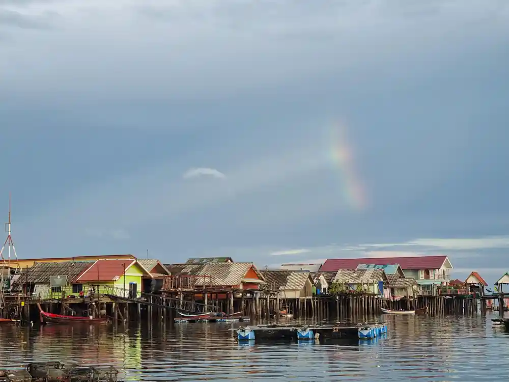 Wooden houses on stilts reflected in calm water
